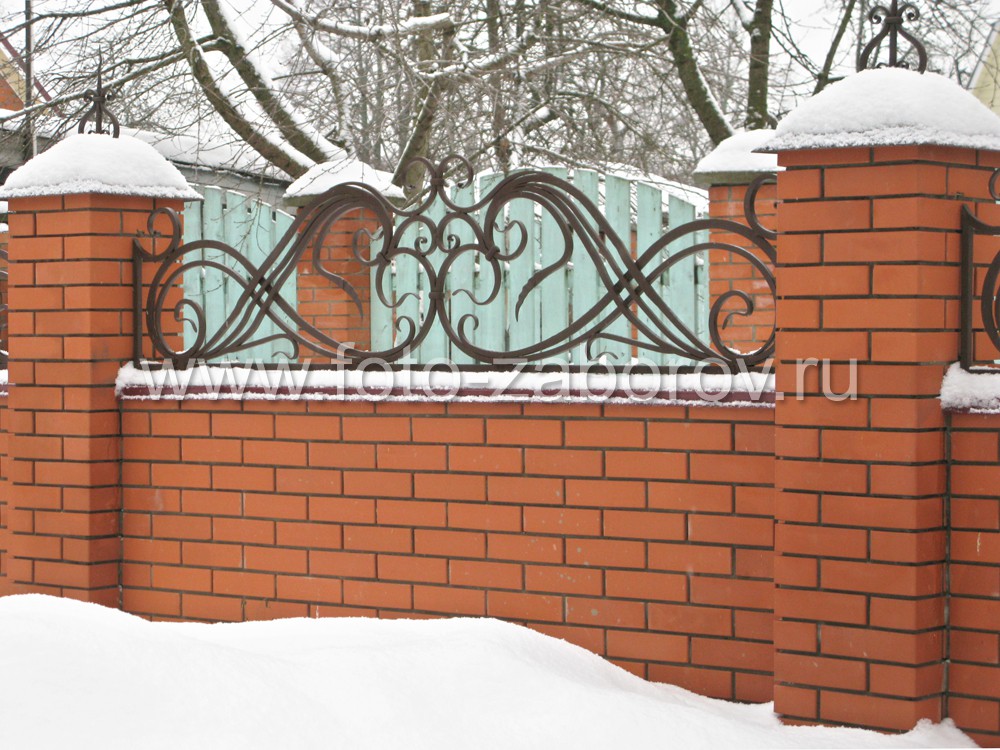 Фото Невысокий забор из красного кирпича с массивными коваными узорами-завитками в верхней части