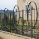 Смелое дизайнерское решение: массивные металлические циклоиды поверх классической конструкции делают этот кованый забор неподражаемым.
