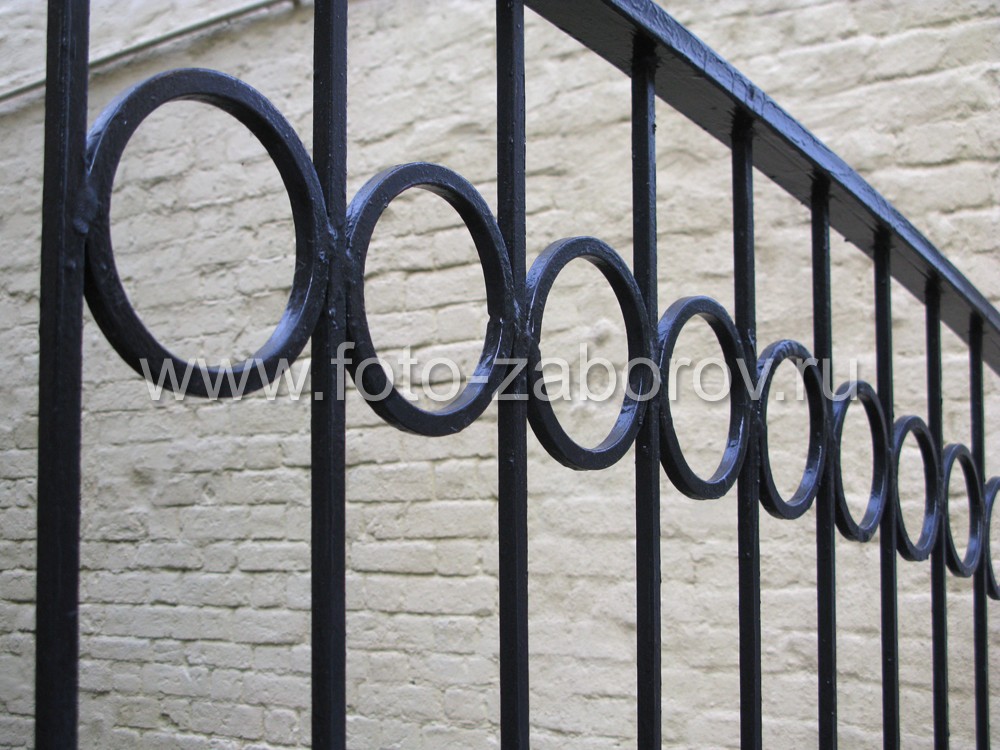 Фото Простой изящный металлический забор с кованым декором. Средняя секция - в виде широкой